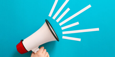 Female hand with megaphone on color background