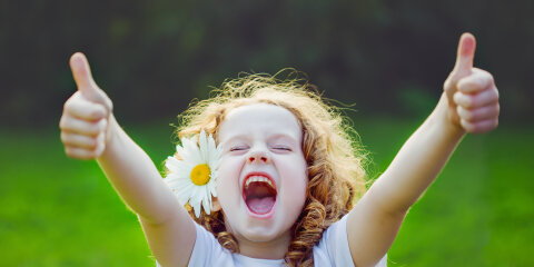 Laughing girl showing thumbs up.