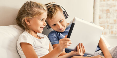 Cute brother and sister enjoying tablet at home